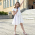 Young girl in a white dress standing on a paved area with a building in the background